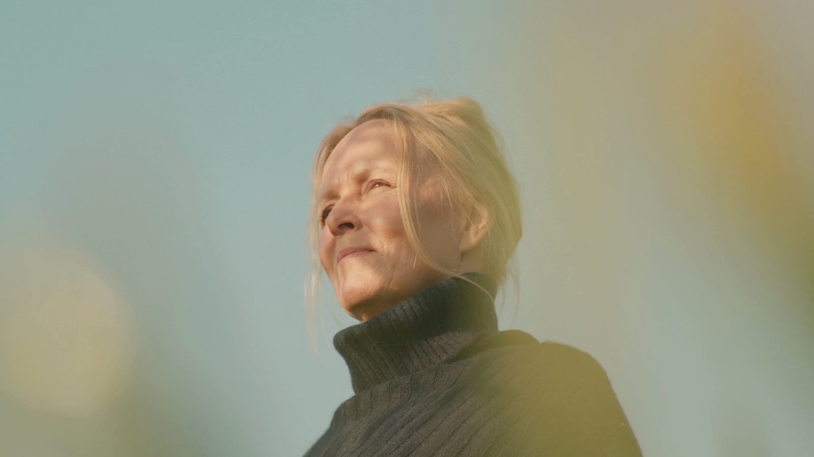 A woman in her fifties turning her face to the sun in golden light
